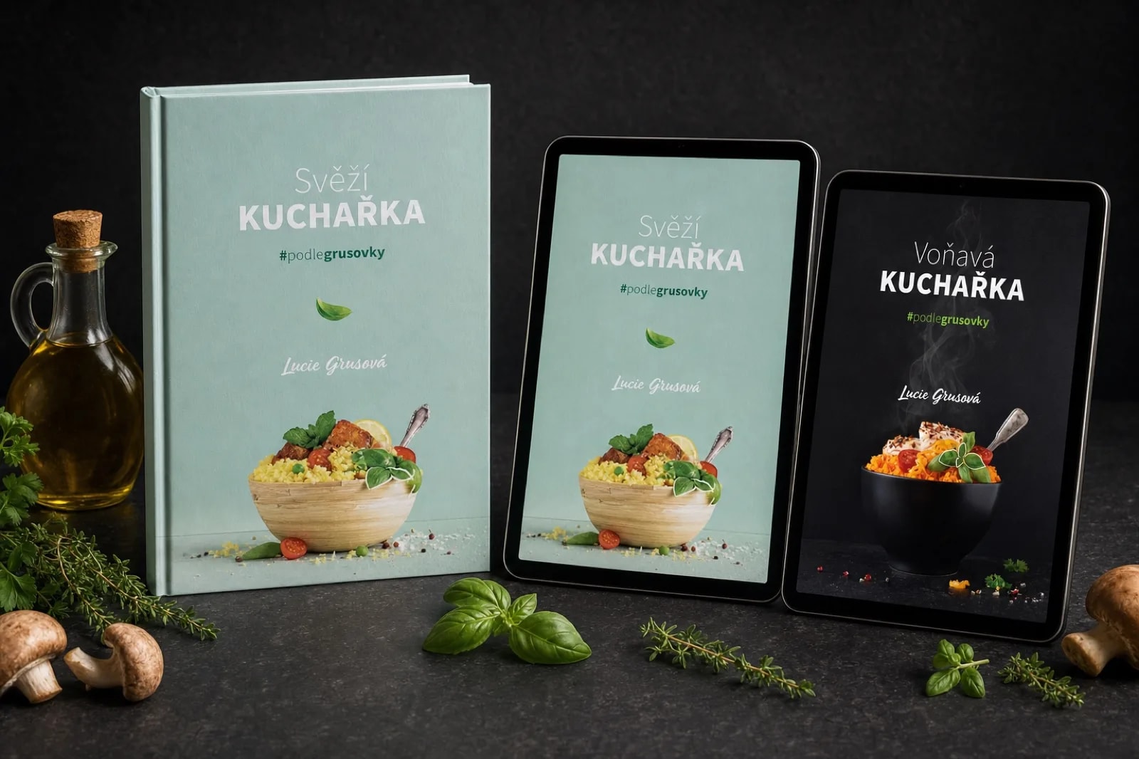 Tištěná Svěží kuchařka vedle dvou tabletů se Svěží a Voňavou kuchařkou, studiový snímek na tmavé desce
