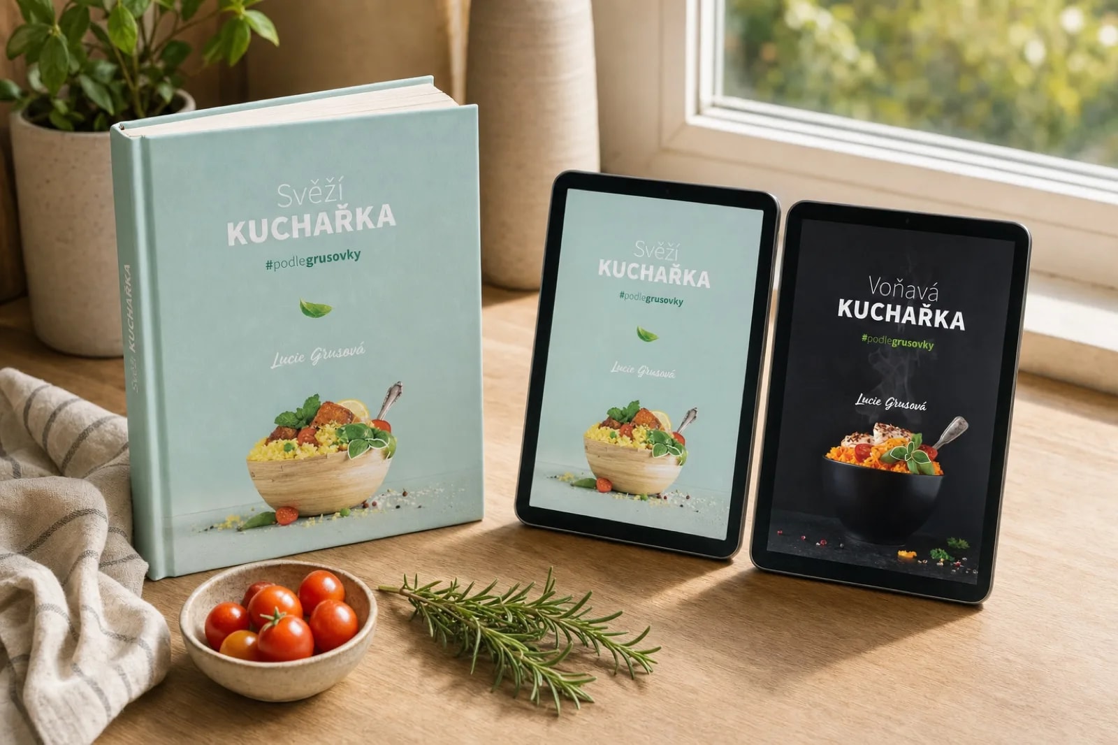 Tištěná Svěží kuchařka a tablety s oběma e-knihami na světlém kuchyňském stole u okna