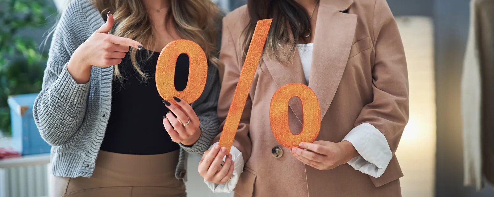 Dvě ženy držící velký oranžový znak procenta