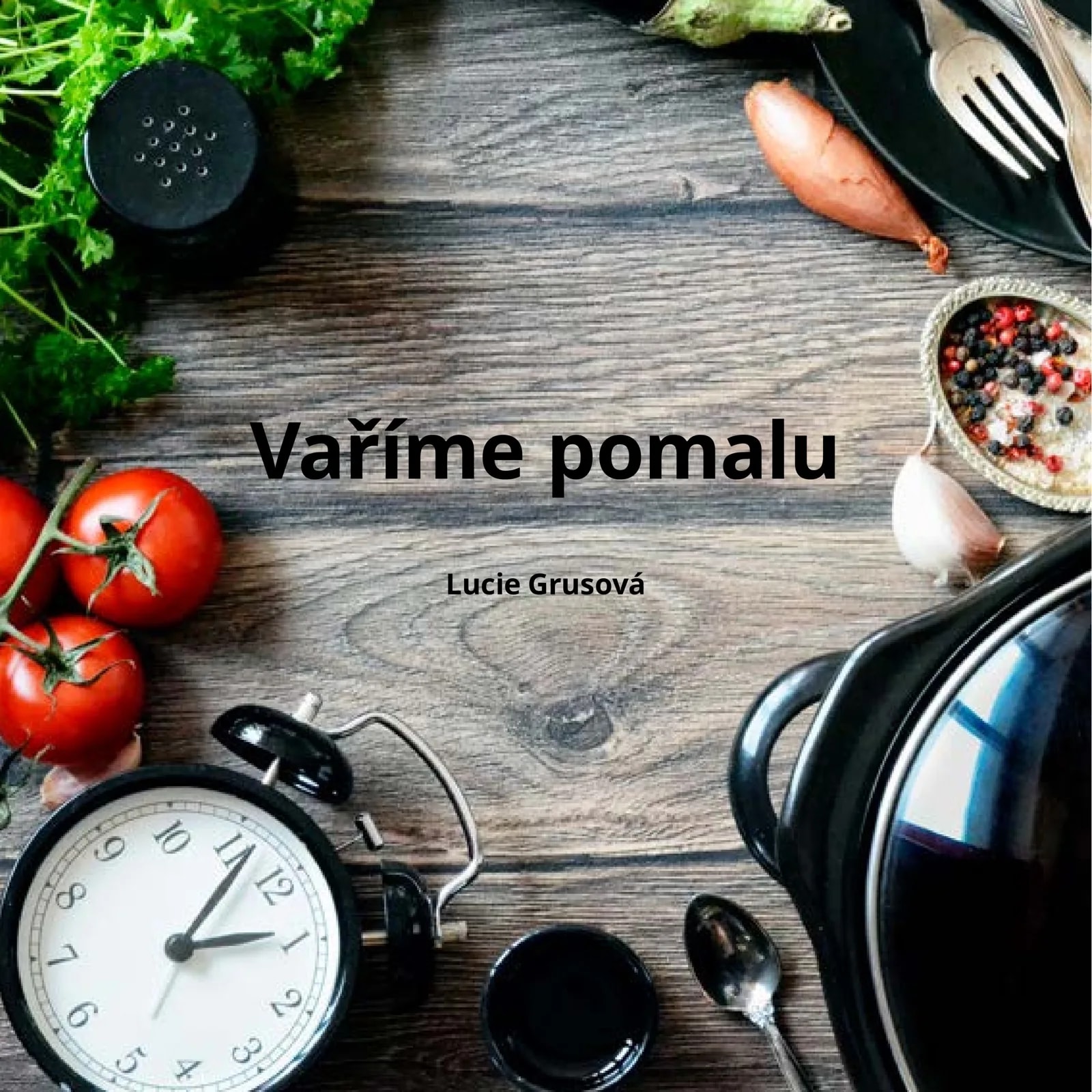 Obálka kuchařky Vaříme pomalu: pohled shora na tmavé ošlehané dřevo s petrželí, černým mlýnkem, rajčaty na větvičce, budíkem se dvěma zvonky a rohem černého pomalého hrnce