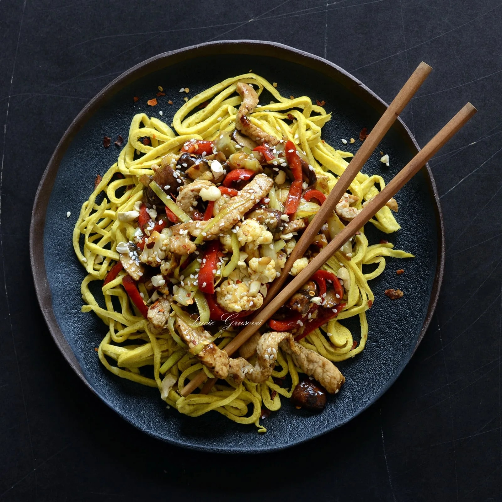 Tmavý talíř s low carb nudlemi, restovaným masem, zeleninou a sezamem