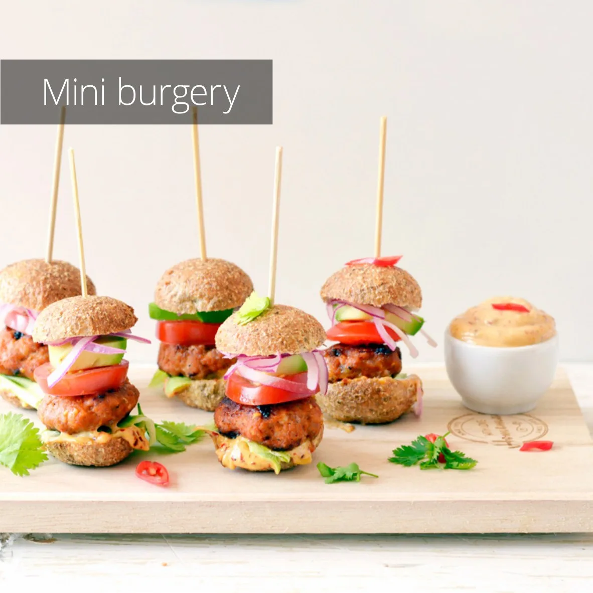 Strana z kuchařky s mini burgery napíchnutými na bambusových špejlích na dřevěném prkénku